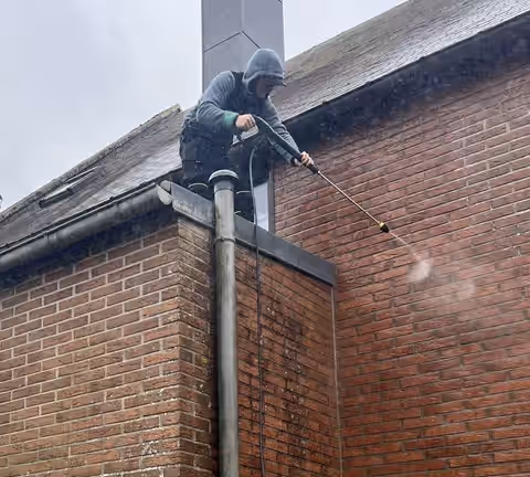Kenzo Thiri, couvreur, sur le toit d’une maison en brique pendant un nettoyage