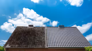 Toiture en tuiles sombres à moitié démoussée, la partie nettoyée à côté de la partie encore couverte de mousse